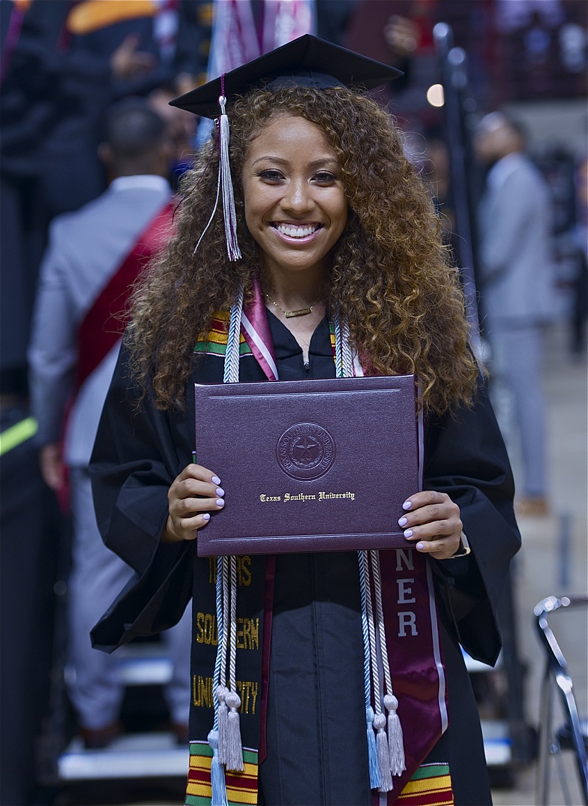 Woman holding degree in graduation gown.